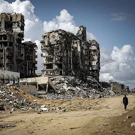 Bombede bygg i Gaza og person som går langs veien