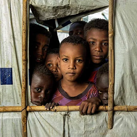 Sør-Sudan: Flere barn står sammen i et telt og stirrer i kamera.