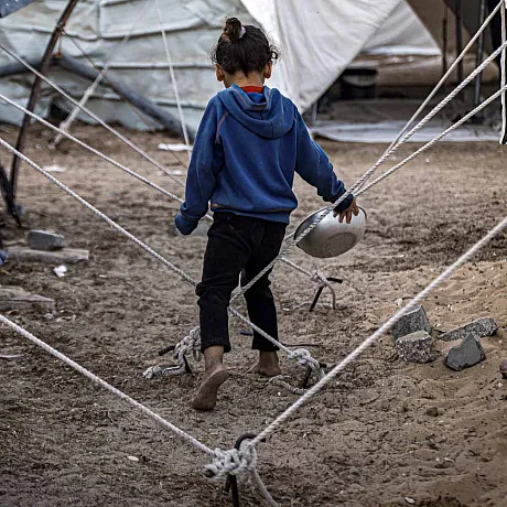 Jente i Gaza går å leter etter mat blant telt.