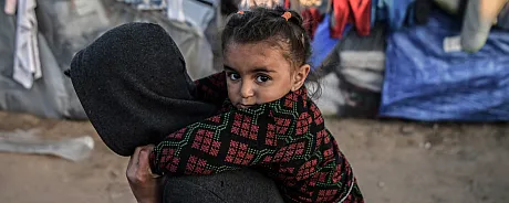 Jente fra Gaza sitter på ryggen til et annet større barn.