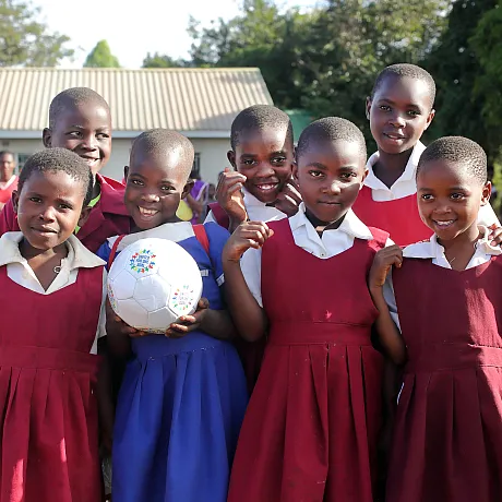 Jenter fra Malawi står samlet og holder i en fotball.