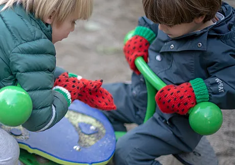 Gutter som leker på en lekeplass. Begge har på seg selbuvottene for fred. 