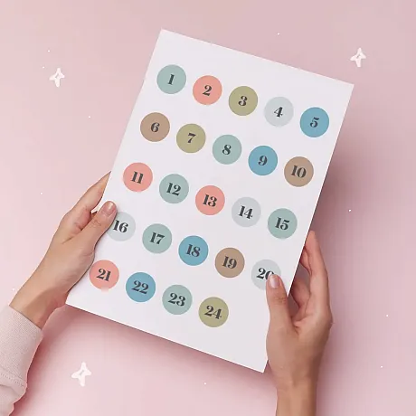 To hender som holder i nummrerte klistremerker som kan brukes til julekalenderen.