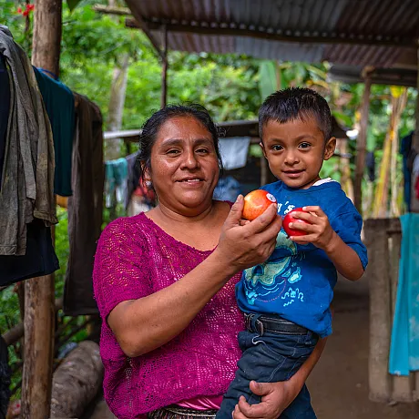 Mor og barn holder epler foran seg