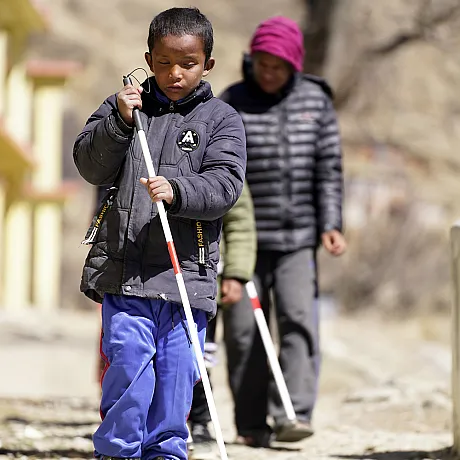 Blind gutt går med blindestokk