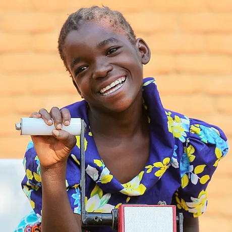 Jente som sitter i rullestol og smiler