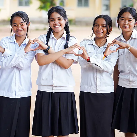 Fem jenter fra Kambodsja lager hjerter med hendene.