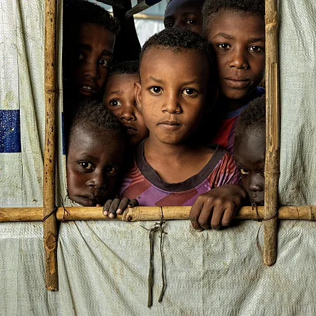 Barn står inne i et telt og ser ut, i Sudan.