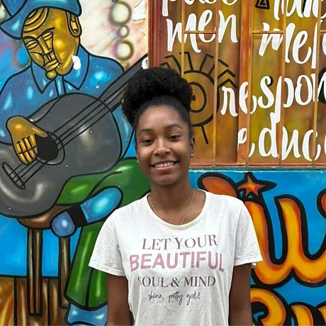 Jente i Colombia står fremfor en vegg med kunst.