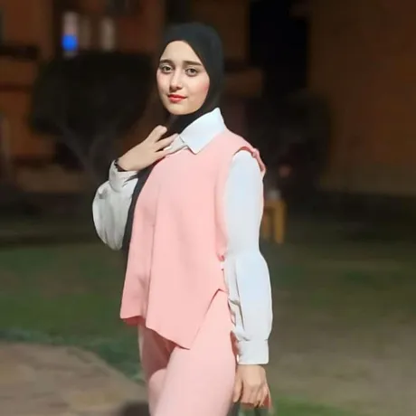 Jente i Egypt i rosa dress og hvis skjorte ser inn i kameraet.