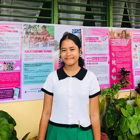 Jente i Filippinene står utenfor skolen sin.