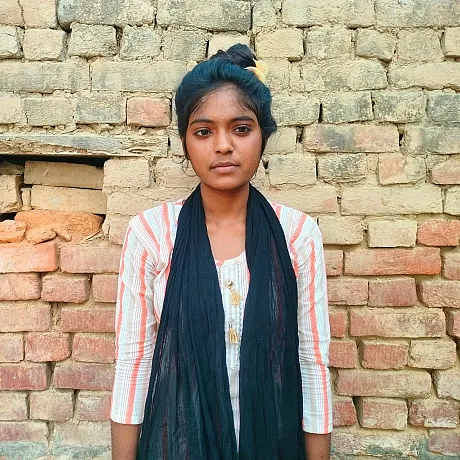 Ung kvinne i India står fremfor en murvegg.