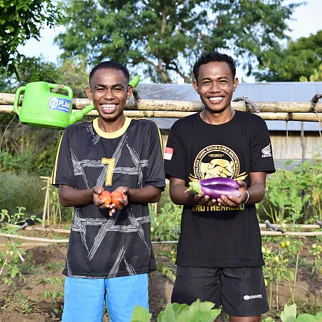 To unge menn i Indonesia viser frem grønnsaker.