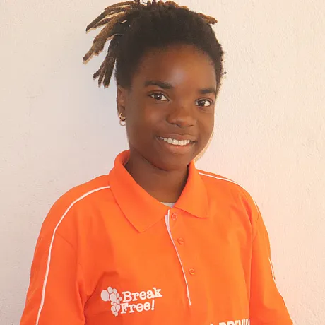 Jente i Mosambik i oransje t-skjorte smiler til kameraet.