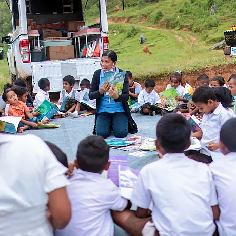En kvinne leser for en skoleklasse utendørs i Øst-Timor.