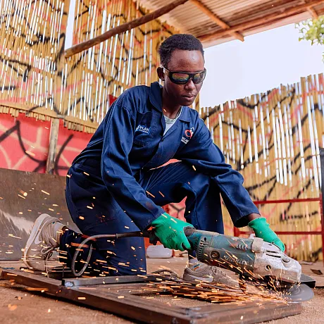 Ung kvinne sveiser utendørs i Rwanda.