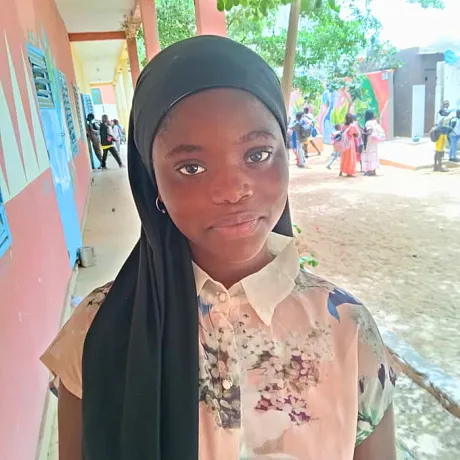 Jente står ved et bygg på skolegården i Senegal.