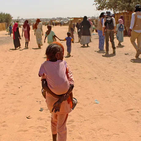 Jente fra Sudan bærer lillesøsteren sin på ryggen. De er i en flyktningleir i Tsjad.
