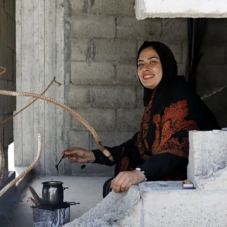 Kvinne brygger te i ruiner i Gaza.
