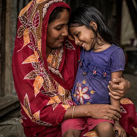 Mor og datter fra Bangladesh. Datteren sitter på fanget til moren.
