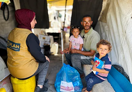 Plan-ansatt deler ut mat til en familie i Gaza.
