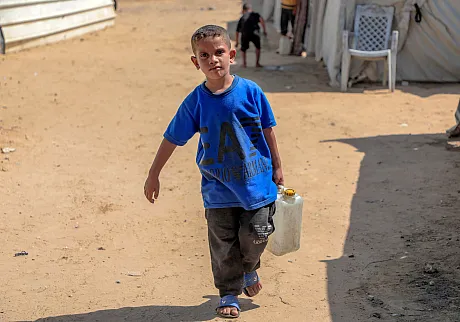 Gutt bærer med seg vann til familien sin i Gaza.