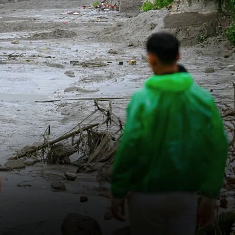 To mennesker står og ser på ødeleggelsene etter flommen i Nepal.