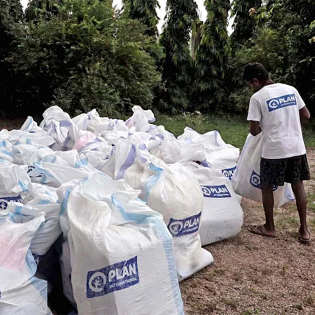 En Plan-ansatt forbereder nødhjelp for distribuering i Nepal.