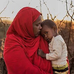 En mor med barnet sitt på armen.